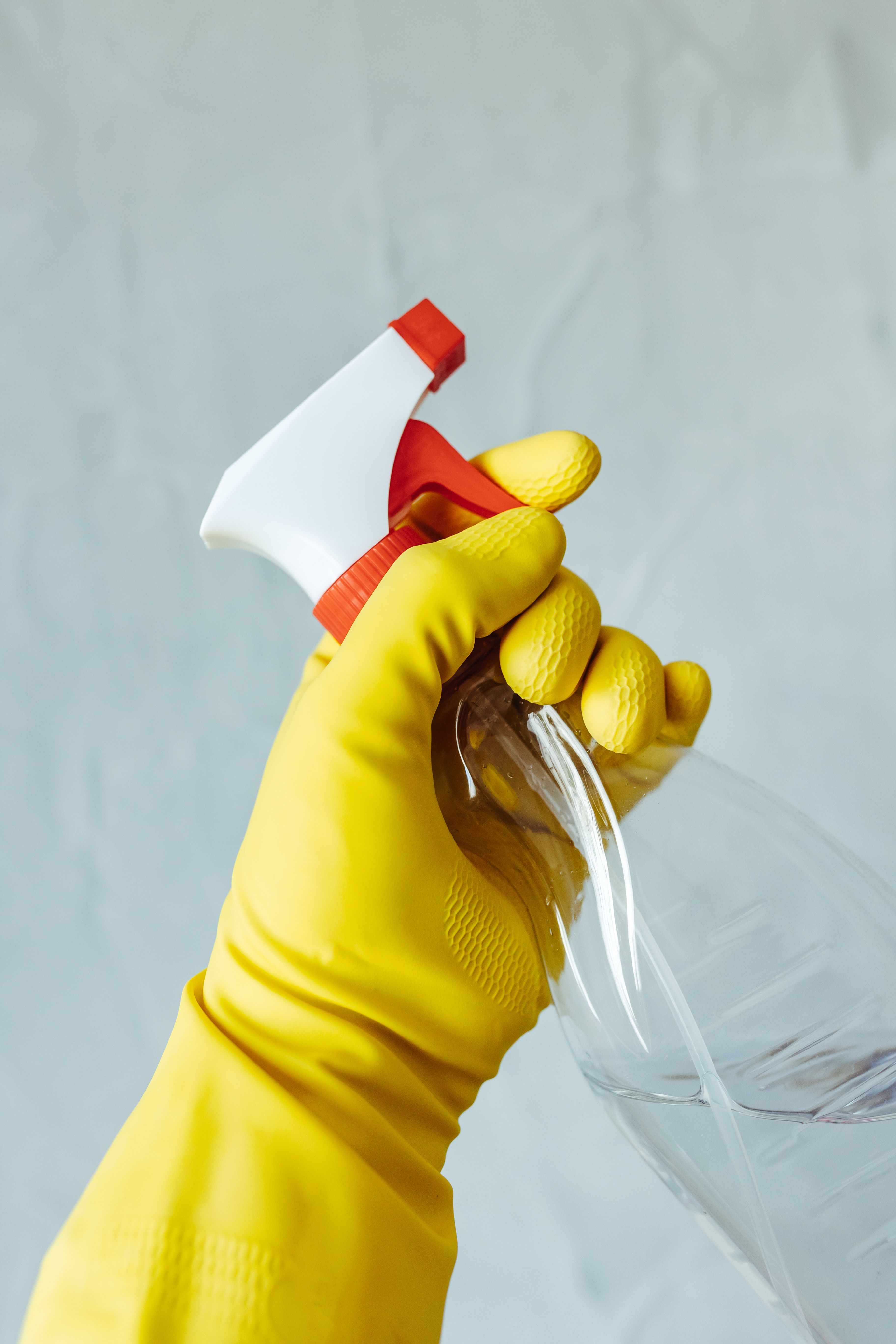 Gloved hand holding a spray bottle while cleaning a Regina home