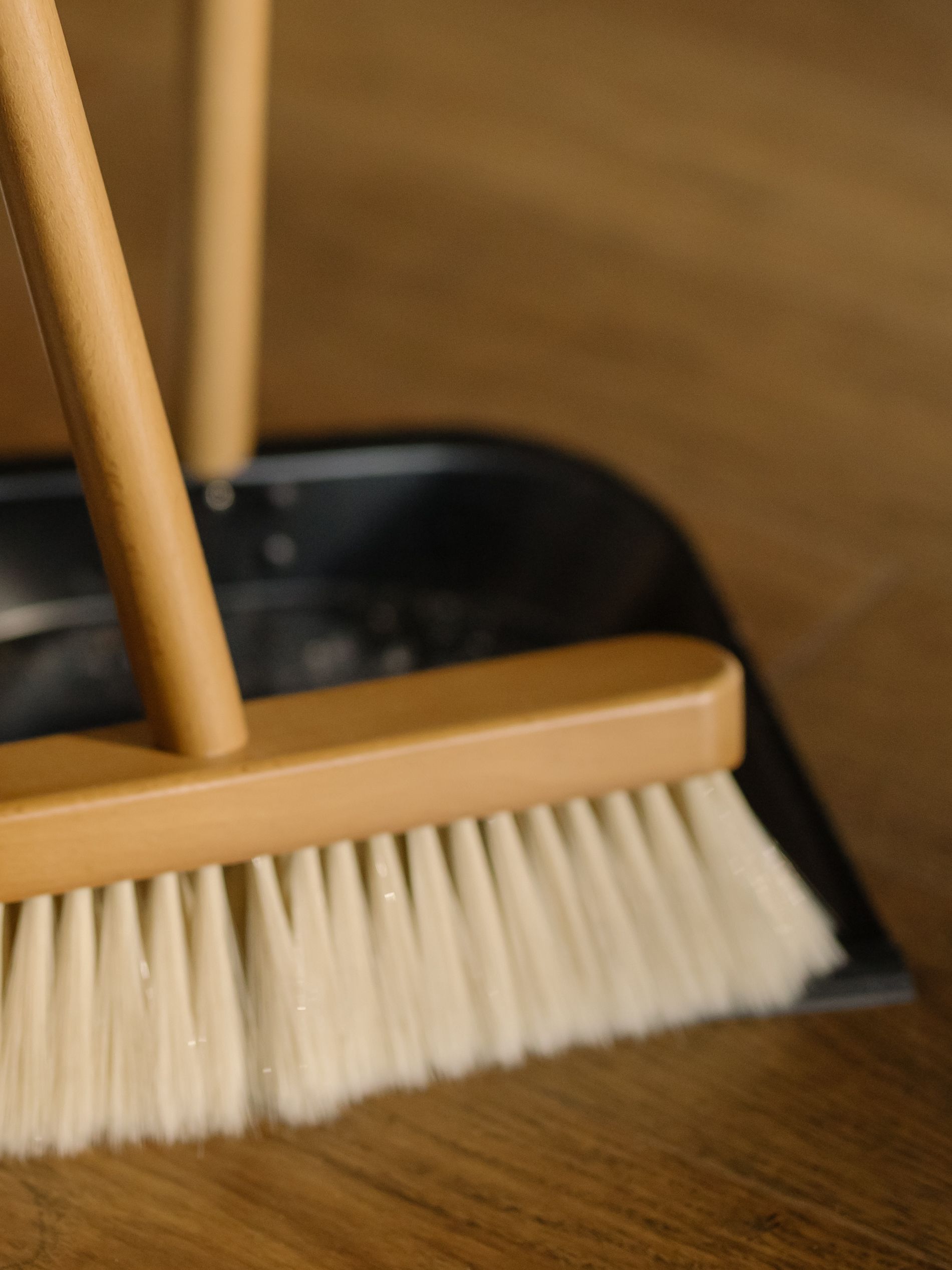 Broom and dustpan on a hardwood floor during a move-out cleaning